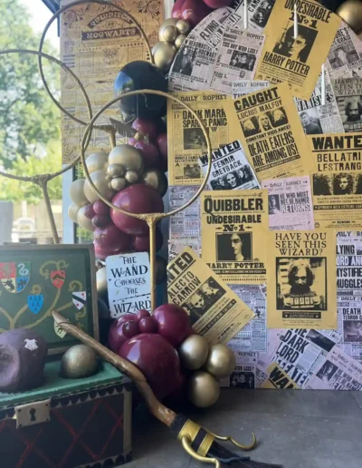 Harry Potter themed prop display with Quidditch hoops, wand, Daily Prophet backdrop and luxury balloon garland.