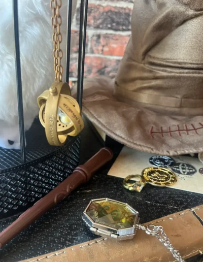 Close-up of Harry Potter themed party props including a wand, sorting hat, time turner and magical accessories.