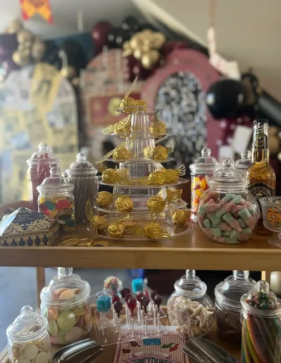 Harry Potter inspired sweet table featuring Honeydukes treats, golden snitch decorations and themed sweets for a wizard-themed party.