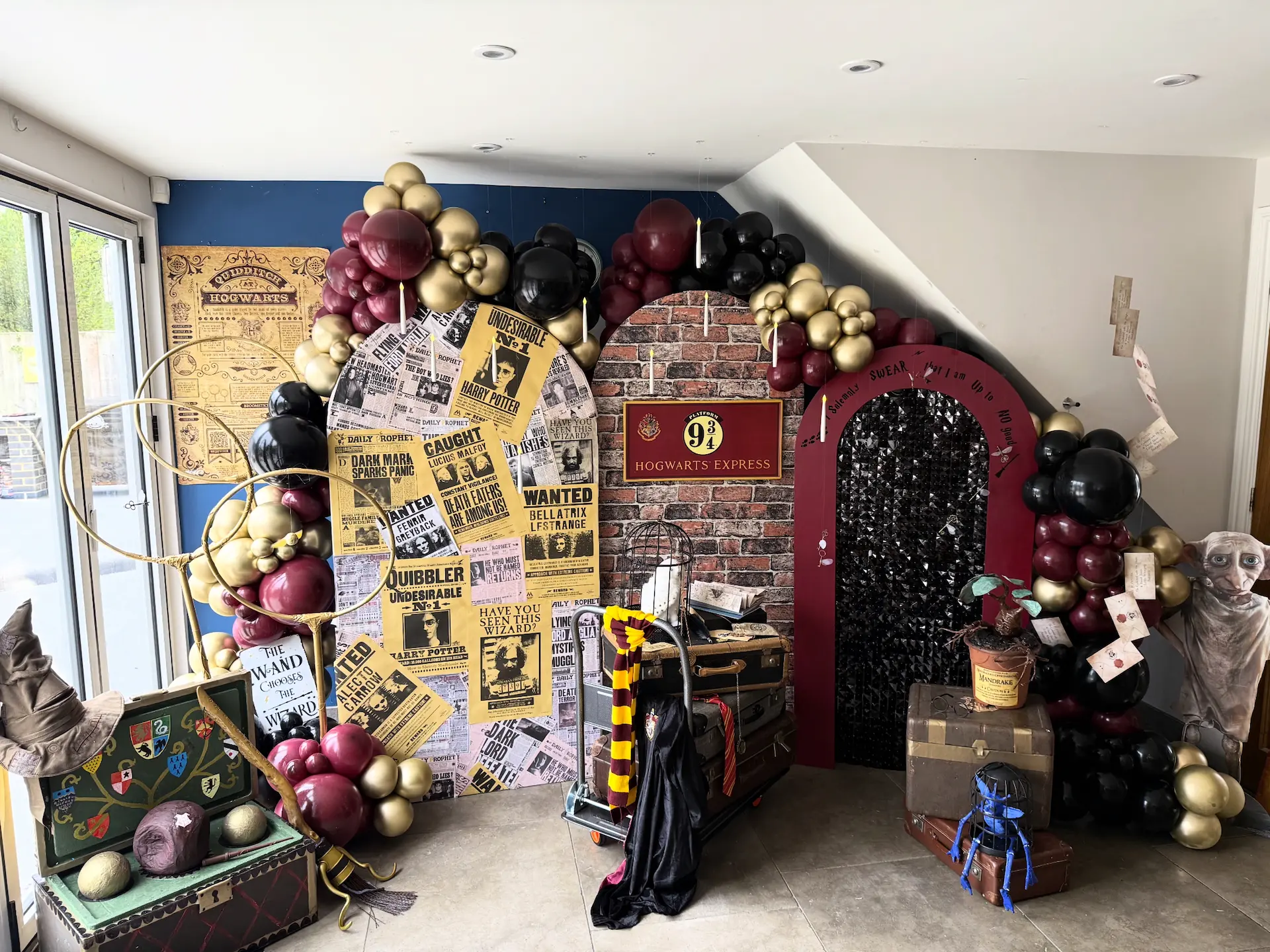 Harry Potter themed birthday party setup with Platform 9¾ backdrop, burgundy and gold balloon garland, Hogwarts props and themed decorations in Bournemouth.